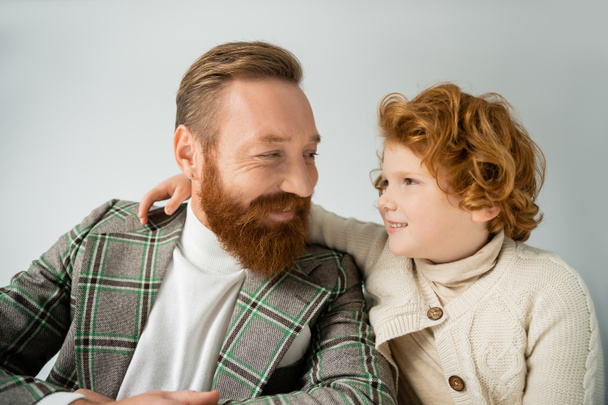 Redhead boy hugging and looking at stylish dad isolated on grey  - Photo, Image