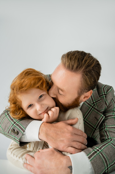 Man in plaid jacket kissing and hugging smiling son isolated on grey  - Foto, immagini