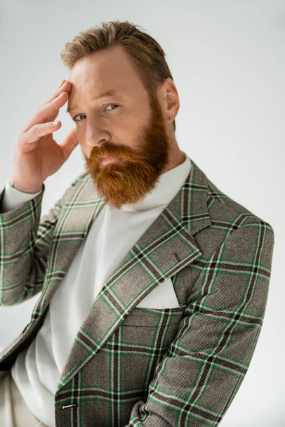 Trendy man in checkered jacket looking at camera while touching forehead isolated on grey  - Fotoğraf, Görsel