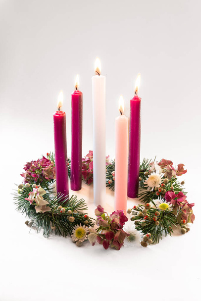 3 velas púrpuras, 1 rosa y una vela blanca en la corona de adviento cristiana decorada y adornada, aislada,  - Foto, Imagen