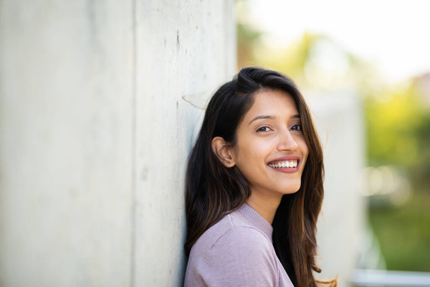 Close up side portrait of smiling young woman leaning against wall - Foto, immagini