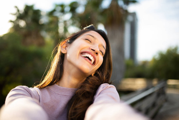 Close up portrait of carefree young woman taking selfie outdoors - Photo, image