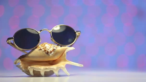 Schale und Sonnenbrille als Reisekonzept auf verschwommenem, buntem Hintergrund - Filmmaterial, Video