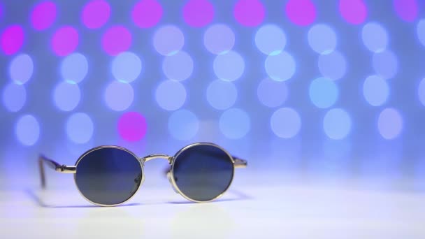Ρετρό γυαλιά ηλίου ως έννοια του ταξιδιού σε ένα θολή φόντο πολύχρωμο - Πλάνα, βίντεο