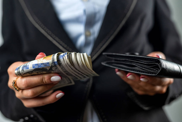 İçinde dolar olan siyah bir cüzdanı tutan bir kadının yakın çekimi. Cüzdanı bol, parası olan bir kadın. - Fotoğraf, Görsel