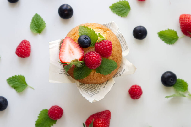 Tuoreita marjoja sisältävä muffini pöydällä mansikoiden, mustikoiden, vadelmien ja mintun kanssa  - Valokuva, kuva