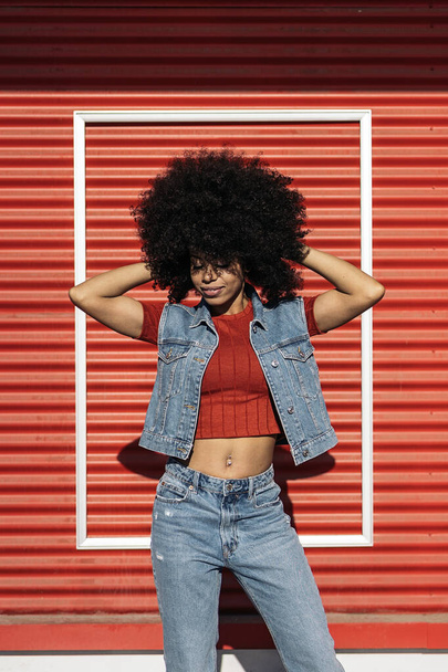 African woman with cool afro hair having fun and posing against red background. - Fotografie, Obrázek