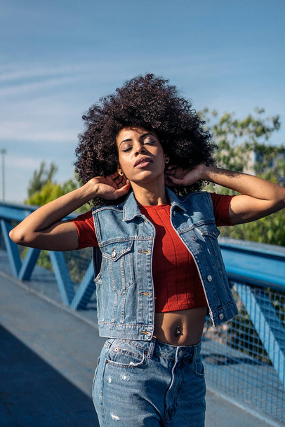 Beautiful african woman with afro hair posing and having fun in the city. - 写真・画像