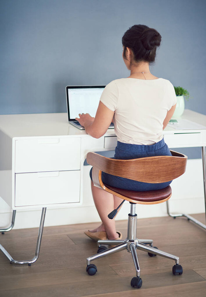 Geen afleiding. Rearview shot van een onherkenbare jonge zakenvrouw die werkt op een laptop in haar kantoor - Foto, afbeelding