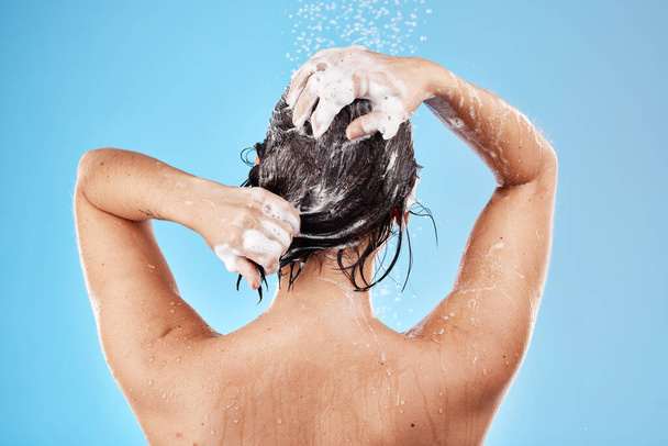 Suihku, hiukset ja shampoo, jossa nainen puhdistaa studiossa sinisellä taustalla hiustenhoitoon tai hygieniaan. Vesi, hyvinvointi ja ylellisyys, jossa nainen pesee ruumiinsa kylpyhuoneessa hoitoon tai hoitoon. - Valokuva, kuva