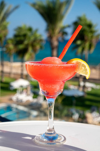 Värikäs jäädytetty vaaleanpunainen Mansikka daiquiri cocktail juoma tarjoillaan lasi ulkona kahvilassa näkymät sininen meri ja palmuja, rentoutua ja loma merellä - Valokuva, kuva