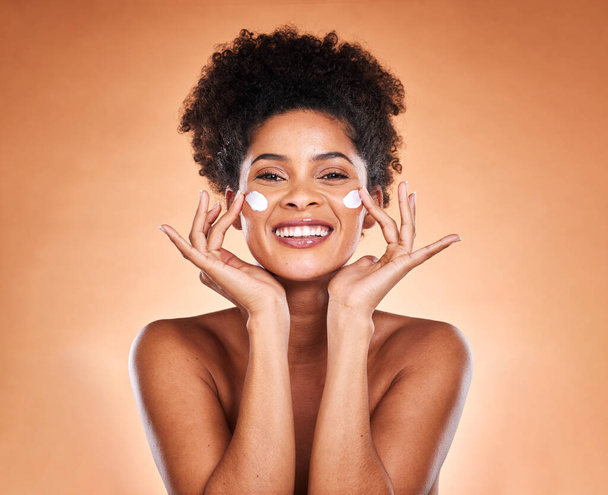 Sunscreen, black woman with skincare product on face and beauty in studio with orange background in Atlanta. Healthy smile for portrait, collagen cream for facial glow or cosmetic lotion for acne. - Foto, Imagem