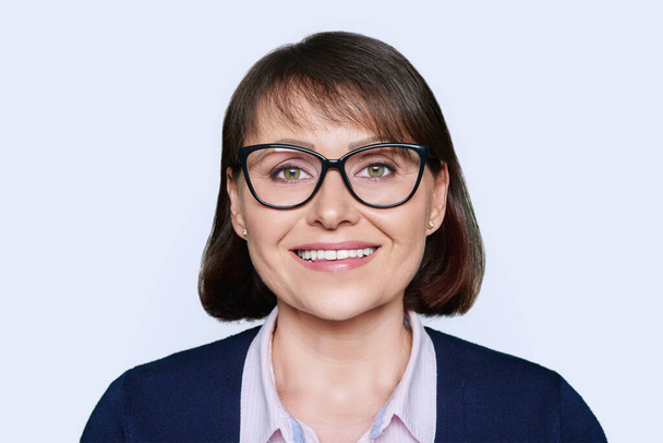 Headshot portrait of business smiling 40s woman looking at camera, white studio background. Positive middle aged woman in business clothes with glasses - Photo, Image