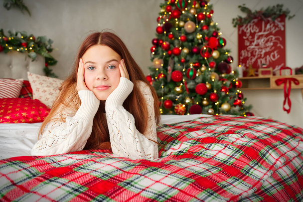 felice ragazza adolescente sognando a letto sopra le luci dell'albero di Natale su sfondo. vacanze e concetto di persone. - Foto, immagini
