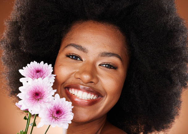 Black woman, face or afro hair with daisy flowers on studio background for gentle skincare, vibrant glow or organic dermatology. Zoom, portrait or happy smile beauty model with natural hair and plant. - Foto, Imagem