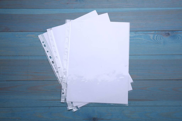 Punched pockets with paper sheets on light blue wooden table, flat lay - Foto, Imagem