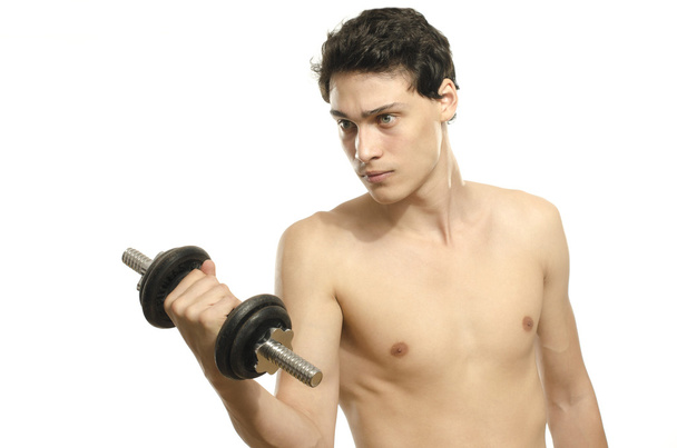 Skinny man training his bicep muscle. Beautiful teenager lifting a dumbbell.Anorexic young man training to become stronger - Фото, изображение