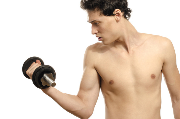 Skinny man training his bicep muscle. Beautiful teenager lifting a dumbbell.Anorexic young man training to become stronger - Zdjęcie, obraz