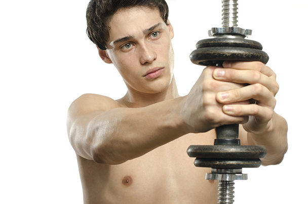 Skinny man training his bicep muscle. Beautiful teenager lifting a dumbbell.Anorexic young man training to become stronger - Zdjęcie, obraz