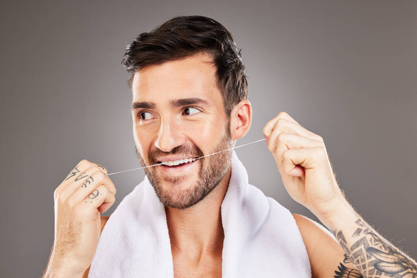 Teeth, dental floss and cleaning man in studio isolated on gray background. Oral care, dental health and happy male model from Australia tooth flossing for gum care, wellness or healthy mouth hygiene. - Fotó, kép