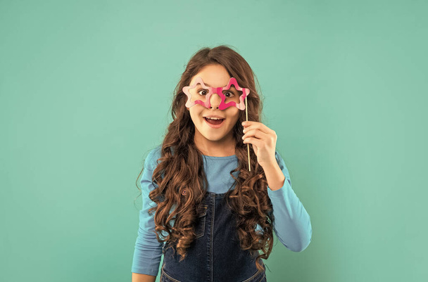 happy teen girl has curly hair hold party accessory of glasses, childhood. - Фото, изображение