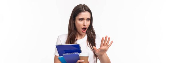 Education, university and studying concept. Close-up portrait of shocked young woman holding notebooks and learning material staring at her hand with shock as she broke her finger, need go salon. - Photo, Image