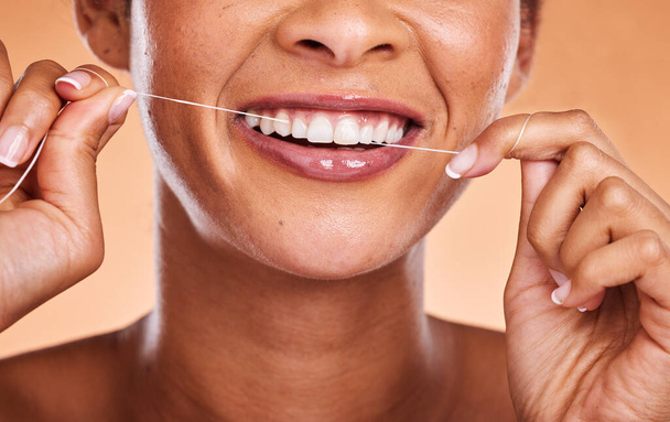 Woman, hands and teeth with smile for dental floss, skincare or personal hygiene against a studio background. Closeup of female smiling and flossing in cosmetics for oral, mouth or gum care treatment. - Fotografie, Obrázek