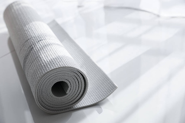 Rolled karemat or fitness mat on floor indoors, space for text - Φωτογραφία, εικόνα