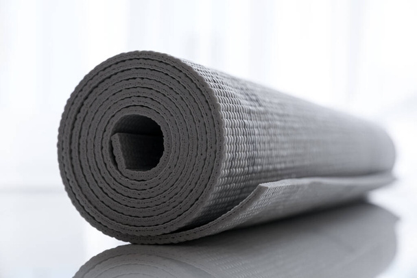 Rolled karemat or fitness mat on tiled floor, closeup - Foto, Imagen