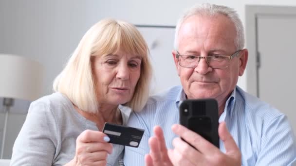 aposentados americanos comprar bens on-line com um cartão de crédito. Idosos aposentados em casa pagam contas de serviços públicos usando um smartphone - Filmagem, Vídeo