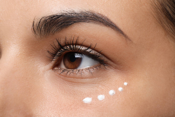 Woman with eye cream on white background, closeup. Skin care - Fotó, kép