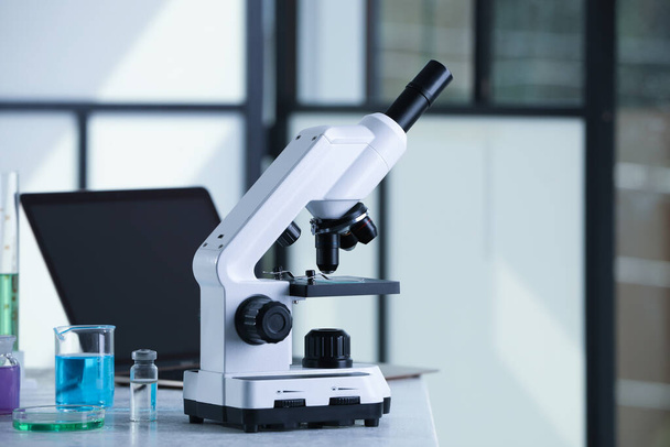 Microscopio moderno con tobogán de vidrio sobre mesa blanca en laboratorio, espacio para texto - Foto, Imagen