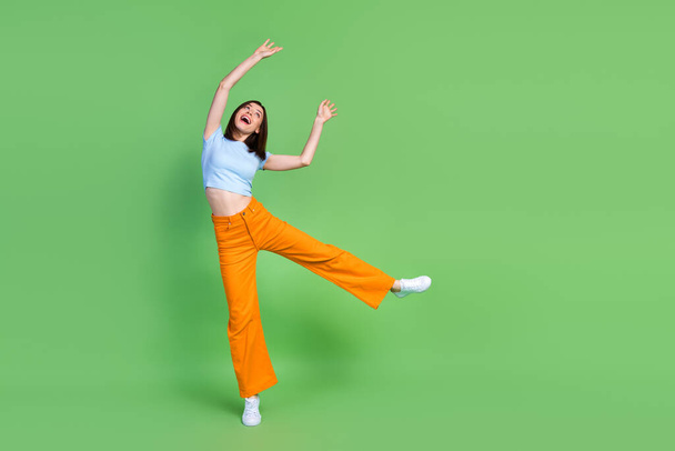 Full length photo of overjoyed astonished person dance look empty space isolated on green color background. - Zdjęcie, obraz