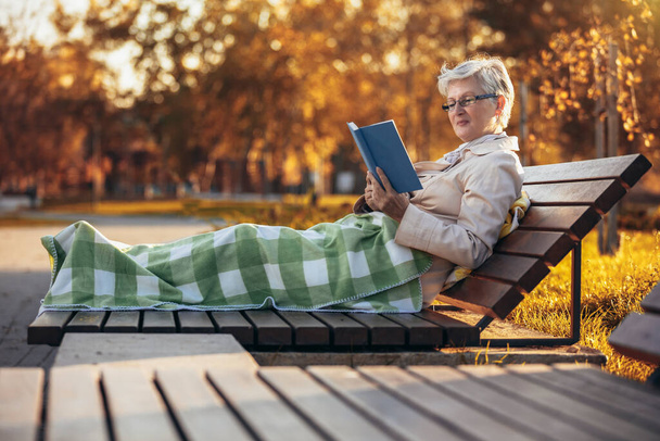 Idős nő pihentető parkban regény - Fotó, kép