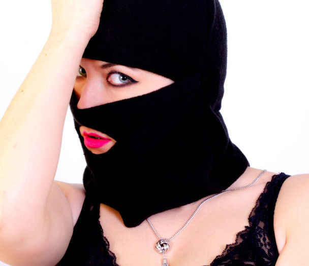 Portrait of an adult woman in a criminal mask on a white background - Fotó, kép