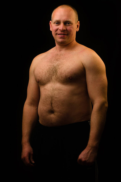 Portrait of an adult man with big muscles on a black background - Foto, Bild