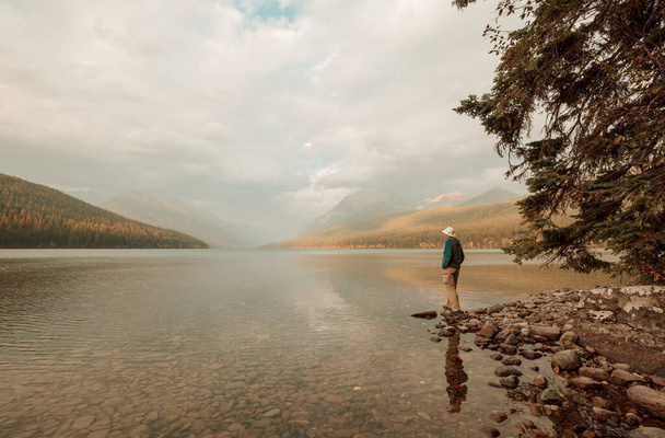 Ένας άντρας ξεκουράζεται δίπλα στην ήρεμη λίμνη. Διακοπές χαλάρωσης - Φωτογραφία, εικόνα