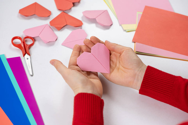 バレンタインデーに折り紙の心を作る。自分の手で紙を作る工芸品 - 写真・画像