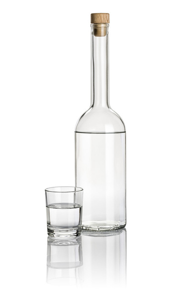 Liquor bottle and drinking glass filled with clear liquid - Foto, Bild