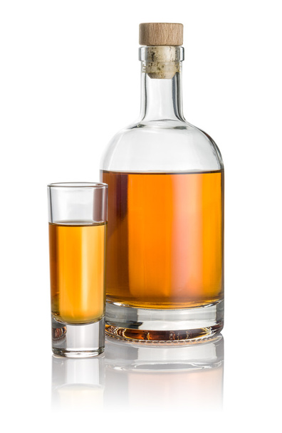 Bottle and high shot glass filled with amber liquid - Photo, Image