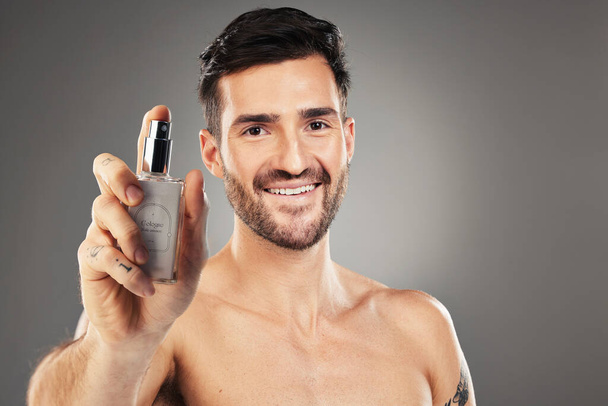 Man, face or body care cologne bottle on gray studio background for morning grooming routine, aroma fragrance or scent spray. Portrait, smile or happy male perfume model and parfume product container. - Foto, Imagem