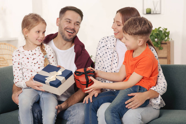 Happy family presenting each other with gifts on sofa at home - Foto, Bild