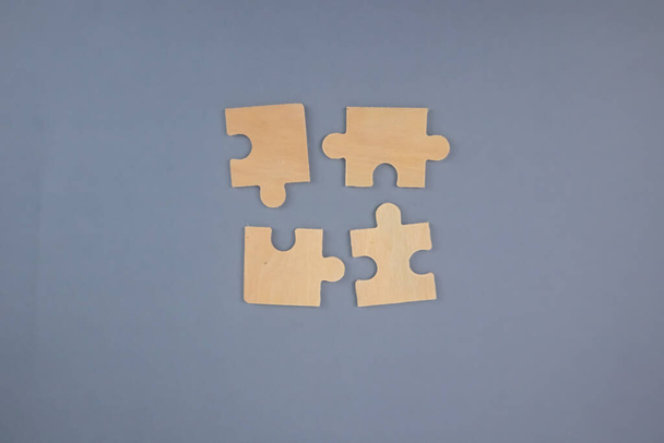 4 hölzerne Puzzleteile auf grauem Hintergrund. - Foto, Bild