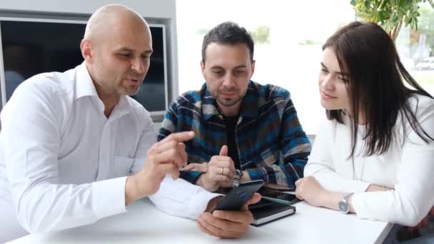 Een makelaar toont eigendommen met behulp van een tablet. Een familie koopt een nieuw huis op krediet. Bankleningen. Het werk van een makelaar - Video
