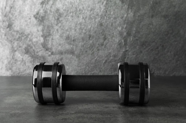 Metal dumbbell on table against grey background. Space for text - Foto, Imagen