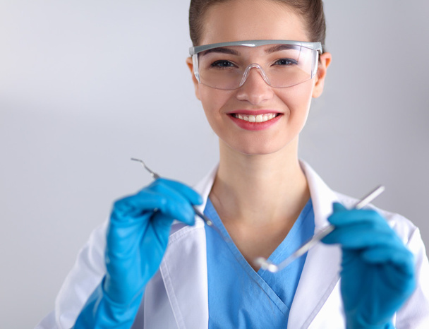 Attractive female dentist with tools , standing on gay background - Fotó, kép