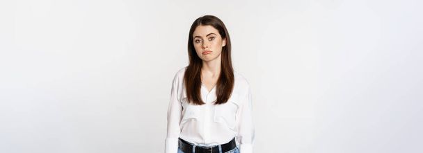 Sad and gloomy woman sulking, looking disappointed and moody, standing upset against white background. - Photo, image