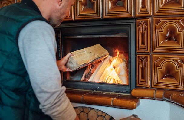 Man putting wood logs in the home mantel fire.Home sweet home and winter countryside holidays concept image - Φωτογραφία, εικόνα