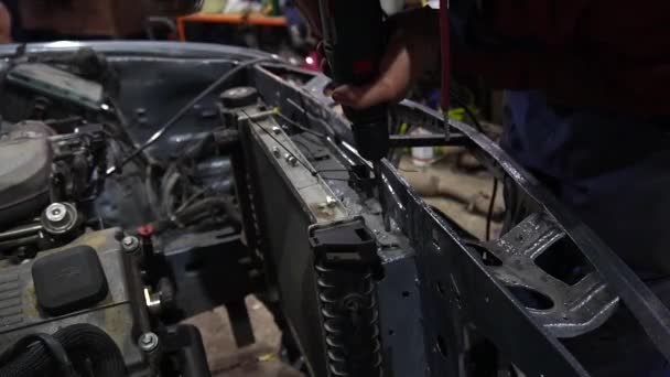 um mecânico desmonta um velho motor de carro sujo em um elevador vermelho para reparação e ajuste - Filmagem, Vídeo