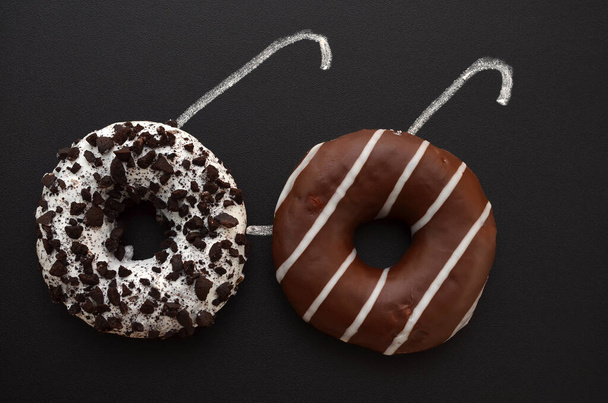 Kreatives Bild von zwei Donuts auf einer Tafel in Form einer Brille - Foto, Bild